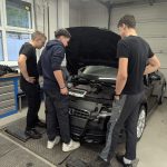 Dijak razlaga dvema učencema, kaj se skriva pod odprtim pokrovom motorja avtomobila.