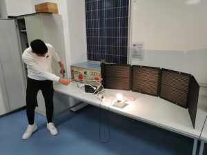 Na sliki je dijak, miza, dela s pripomočki za elektrotehniko.