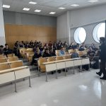 Dijaki sedijo v predavalnici in poslušajo predavanje policista.