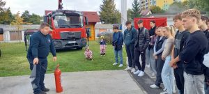 Inštruktor gasilec razlaga pravilno uporabo gasilnega aparata