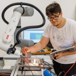 Na sliki sta dijak in robotska roka.