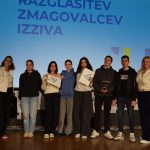 Dijaki na odru, v rokah držijo plakete, za njimi, na platnu, je napis razglasitev tekmovalecev