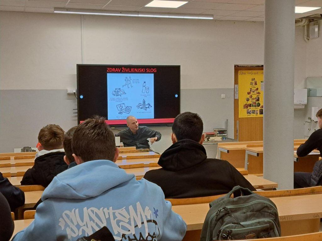 Dijaki v predavalnici poslušajo predavatelja Luko Plavčaka, ki pripoveduje svojo življenjsko zgodbo.