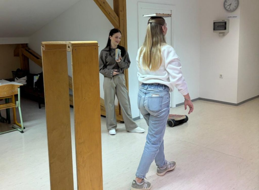 Dijakinja s knjigo na glavi na knjižnem poligonu.