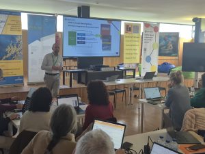 Strokovno srečanje Erasmus+. Učitelji sedijo, se izobražujejo in poslušajo predavatelja.
