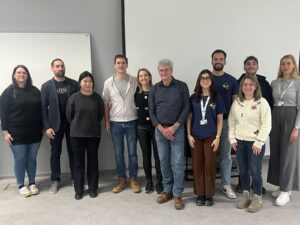 Udeleženci projekta Erasmus stojijo v predavalnici. Za njimi je platno.