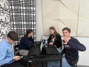 Dijaki sodelujejo pri projektu Erasmus. Na mizi so računalniki. Izpolnjujejo naloge.