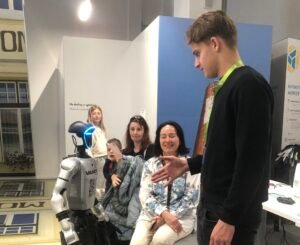 Dijak na festivalu robotike. Zraven njega je humanoidni robot.