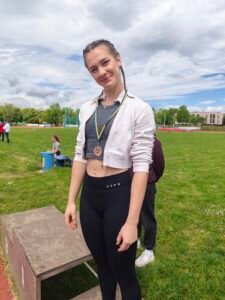 Dijakinja na stadionu z medaljo.